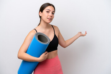 Young sport girl going to yoga classes while holding a mat isolated on white background extending hands to the side for inviting to come