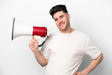 Young caucasian man isolated on white background holding a megaphone and smiling