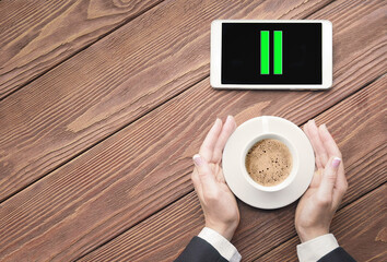 Coffee break. Female hands in business suit touches a cup of coffee and a pause icon on a phone...