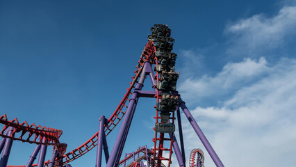 People excitement on red Roller Coaster against blue sky