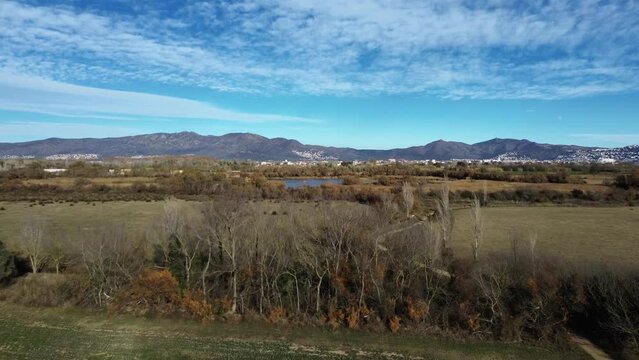 Toma de dron de estanco y humedal espa&ntilde;ol con paisaje de pueblo y monta&ntilde;as de fondo a mediod&iacute;a 