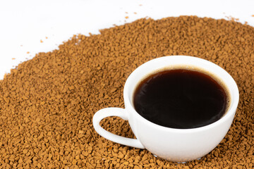 A cup of hot instant coffee on a background of freeze-dried granules