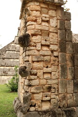 Pillar decorated with stone masks, mayan masks next to the Ossuary, the High Priest Temple at...