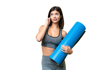 Young sport woman going to yoga classes while holding a mat over isolated chroma key background having doubts and thinking