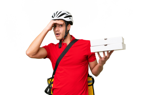 Pizza delivery man with work uniform picking up pizza boxes over isolated background doing surprise gesture while looking to the side