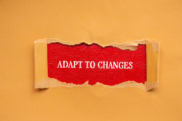Adapt to changes lettering on ripped orange paper with red background. Conceptual photo. Top view,...