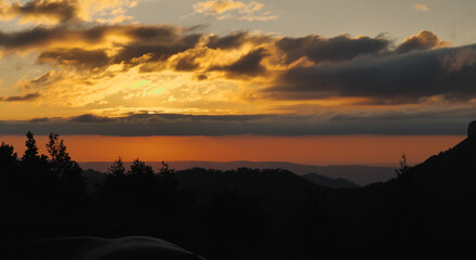 Orange sky at sunset in the mountains. Black silhouettes of the mountain range. Epic sunset in the mountains. Hiking in the mountains.