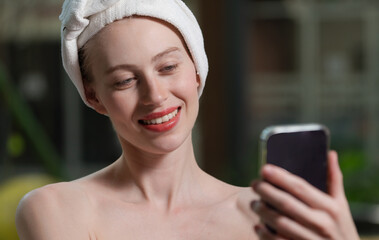 Portrait of close up beautiful caucasian woman in white towel taking video of calm and relaxing nature by using her mobile phone. Pretty girl with beautiful skin take photo. A Side view. Tranquility.
