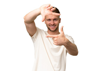 Young blonde caucasian man over isolated background focusing face. Framing symbol