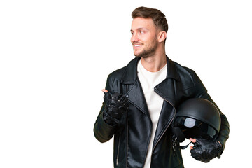 Young caucasian man with a motorcycle helmet over isolated chroma key background pointing to the side to present a product