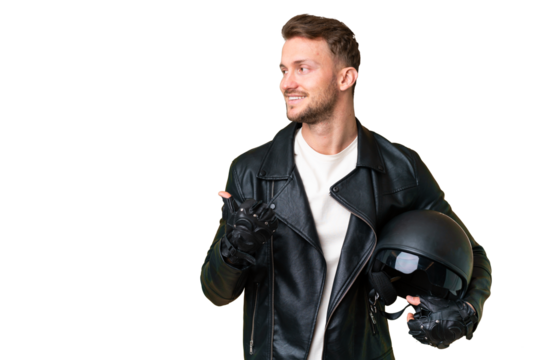 Young caucasian man with a motorcycle helmet over isolated chroma key background pointing to the side to present a product