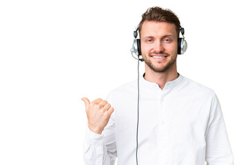 Telemarketer caucasian man working with a headset over isolated chroma key background pointing to...