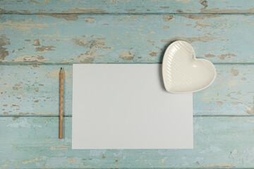 Heart shaped plate, paper, pencil on vintage wooden background. Top view. - 704561885