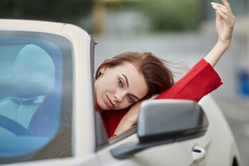 Relaxed young woman sitting on drivers seat in white convertible