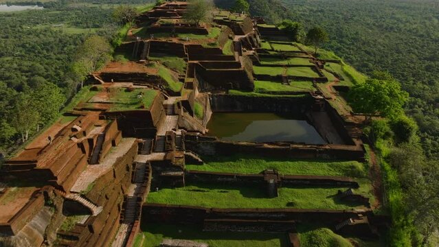 High angle view of terraces in ruins of palace on top of Sigiriya Rock. Tilt up reveal of surrounding wooded landscape. Sigiriya, Sri Lanka