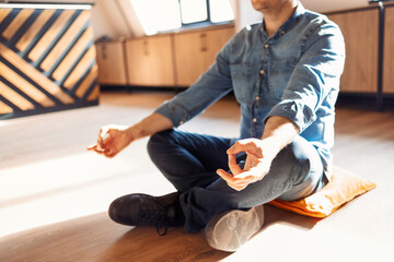 Handsome hispanic man wearing jeans casual shirt sitting on the floor at home relax, doing meditation gesture with fingers. Yoga concept