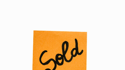 Sold handwriting text close up isolated on orange paper with copy space.