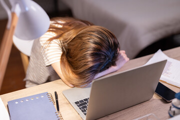 Exhausted asian woman sleep with her open laptop at home suffer from overtime working at night