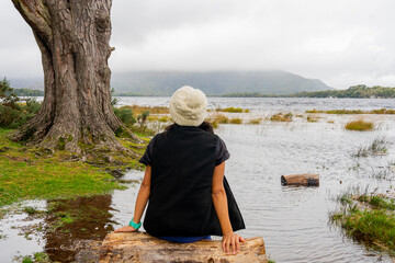 woman with wool hat quietly enjoying her connection with nature in a silent landscape next to a...