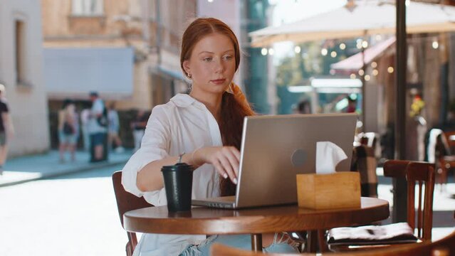 Redhead child girl finish working online distant job study education close laptop in city street cafe restaurant browsing website chatting outdoor during break. Smiling woman tourist looking at camera