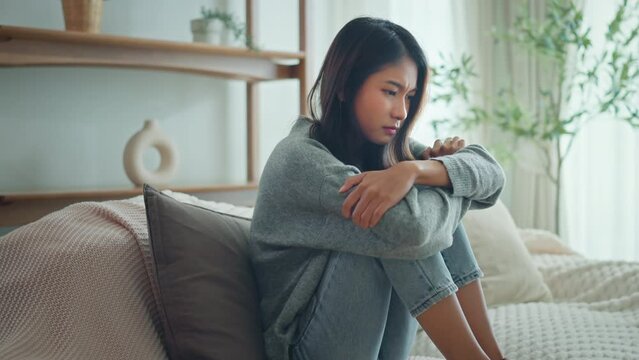 Depressed young woman sitting on couch in the living room at home, Frustrated confused female feels unhappy problem in personal life quarrel break up with boyfriend.
