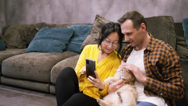 Smile, selfie and a phone, a couple on sofa in living room at home. Friends, lovers and partners, a happy man and Asian woman in love, on couch taking picture or video on smartphone for social media.