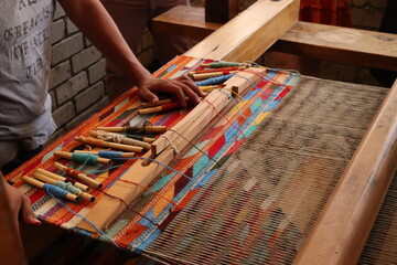 Man in a workshop standing next to a traditional loom, about to weave a colorful carpet, Oaxaca,...
