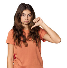 Young Caucasian woman in studio setting showing a dislike gesture, thumbs down. Disagreement...