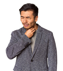 Young Chinese man in studio background suffers pain in throat due a virus or infection.