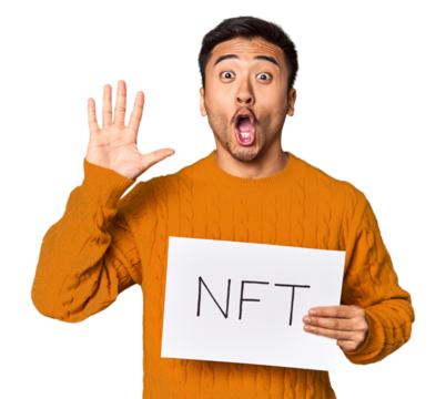 Young Chinese man presenting "NFT" sign in studio environment