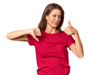 Middle-aged woman portrait in studio setting showing thumbs up and thumbs down, difficult choose concept