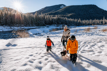 Woman and children walking with their dog in a snowy landscape on a clear sunny winter morning in Alberta, Canada - Powered by Adobe