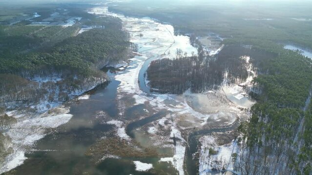 Aerial beautiful view of overflowing river backwater in forest on a sunny winter morning