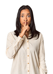 Young Filipina with long black hair in studio keeping a secret or asking for silence.