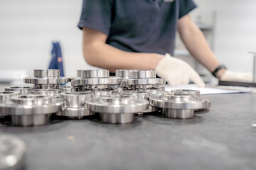 A worker inspects and sorts round parts with holes for assembling them into components and...