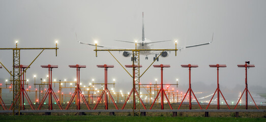 Aircraft during landing, with runway landing lights in front, foggy and rainy weather.