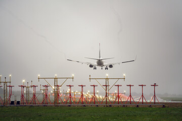 Aircraft during landing, with runway landing lights in front, foggy and rainy weather.