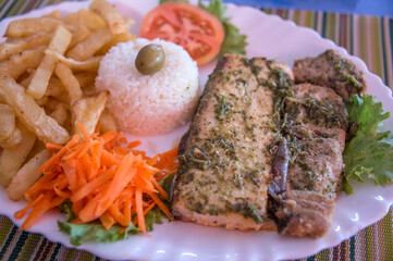 Bandeja con pescado adobado, arroz, ensalada y patatas fritas