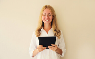 Fototapeta premium Portrait of happy smiling caucasian young woman employee with digital tablet computer or folder with documents in office