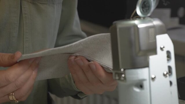Close-up of a shoemaker cutting pieces of leather on a table in a workshop. A female tailor traces patterns on pieces of leather and prepares blanks with a knife for making shoes. Shoe making process