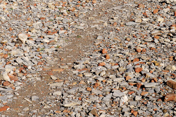 Broken bricks and gravel on the dirt road surface