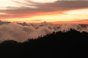 The landscape around San Jose del Pacifico at sunset, clouds, hills and a colorful sky, Oaxaca,...