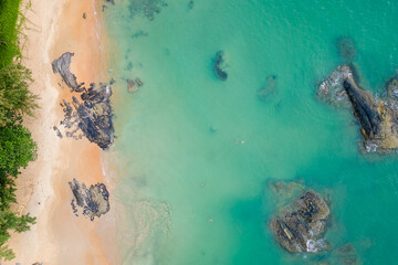 Overhead aerial view of a small, sandy tropical beach and shallow ocean