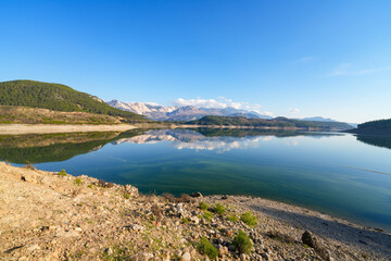 Reflection of trees and green leaves in the lake water. Liquidambar orientalis protected area in Burdur Turkey. Karacaoren ( barrage ) dam lake. Panorama.