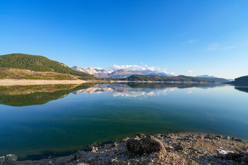 Reflection of trees and green leaves in the lake water. Liquidambar orientalis protected area in Burdur Turkey. Karacaoren ( barrage ) dam lake. Panorama.