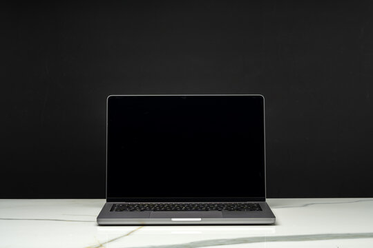 Open laptop with black screen against black background