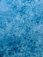 Macro of snow flaces on a light blue surface 
