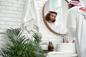 Young Arab man getting ready and looking at the mirror in the bathroom