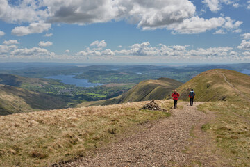 Windermere and Ambleside with hikers seen from the slopes of Farifield on the Fairfield Horseshoe, Lake District, UK