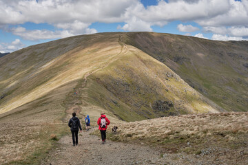 Hikers with dog descend Great Dodd on theri way up to the summit of Fairfield, on the Fairfield Horseshoe, Lake District, UK